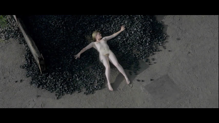 Девушка обнажённая лежит на чёрных камнях в окружении мужчин